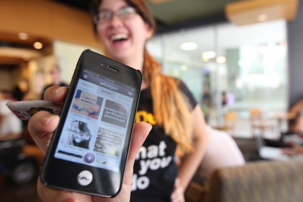 Marketing senior Jennifer Capodiferro shows off the new Whisper application, which lets its users share photos and personal secrets anonymously. The application also features a geographic interphase which allows people to share where they are. (Photo by Dominic Valente)