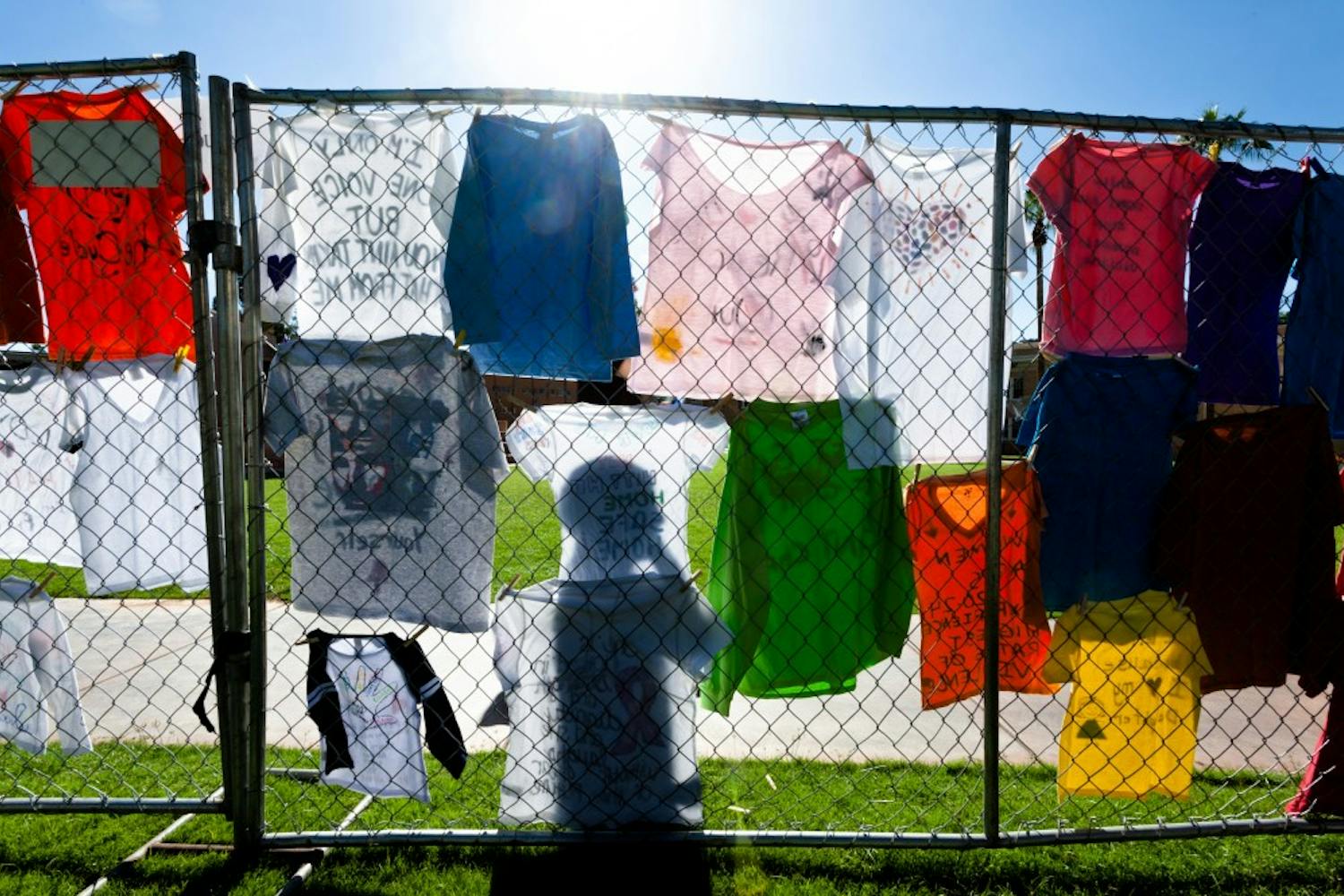 A pedestrian walks past a display of t-shirts put up by the Clothesline Project on Tuesday, Oct. 28, 2014, on Hayden Lawn in Tempe. The project sought to bring awareness to and end the stigma surrounding gender-based violence.