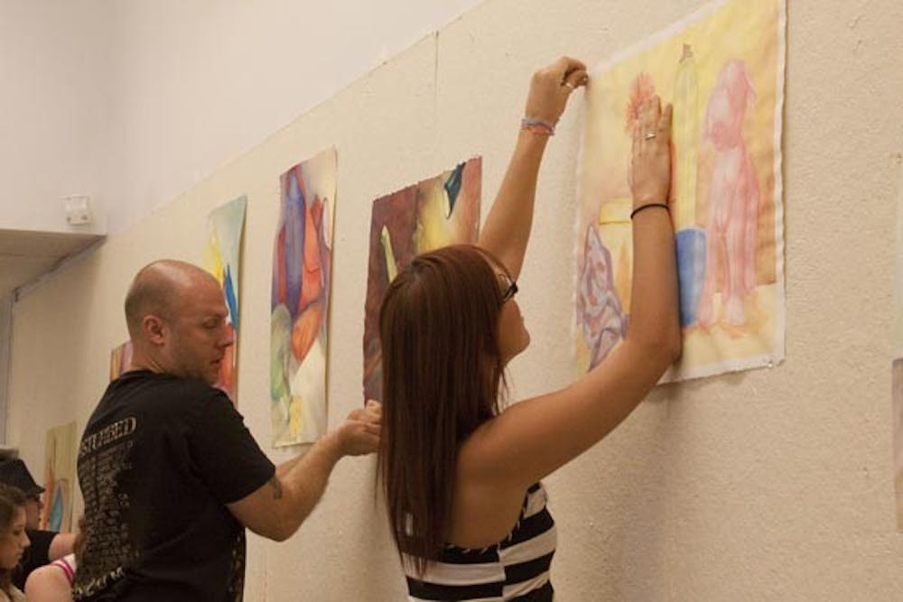 ARTISTIC CRITIQUE: : Art students hang up their pieces of work for critique during class on Monday afternoon. (Photo by Annie Wechter)