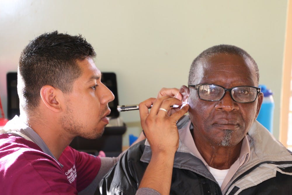 An ASU student from Hearing for Humanity checks the ears of a patient in Malawi during last year's trip.&nbsp;