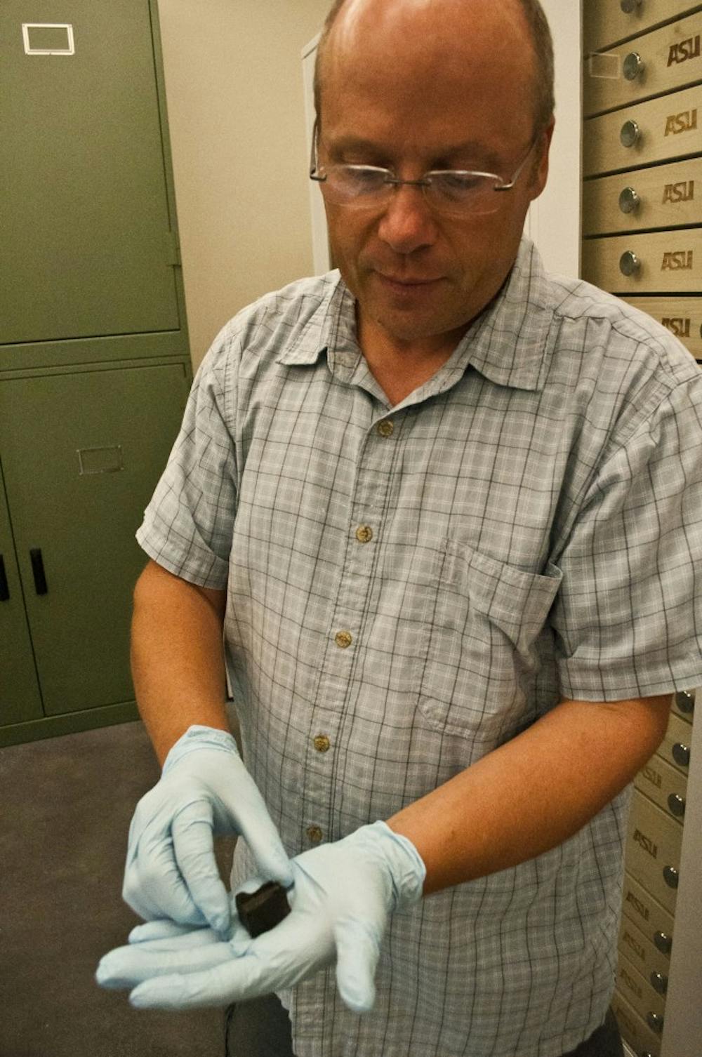 Dr. Lawrence shows the new addition to the collection of other minerals occupying space in the Interdisciplinary 4 building.  This meteorite was broken and shared with a few other colleges to study.  (Photo by Katie Dunphy)