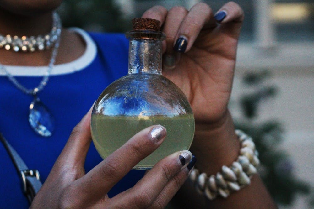 A student discusses the importance of her homemade natural remedy, a perfume made from citrus trees, in front of the Lattie Coor Hall on Tuesday, March 22, 2017. 