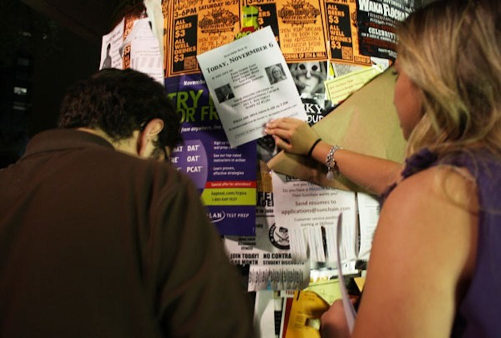 ASU graduate and second-year law student Saman Golestan and transborder studies junior Isabella Leavitt  hung polling location flyers on kiosks and in University housing buildings around the Tempe campus on Monday night. (Photo by Jessie Wardarski)
