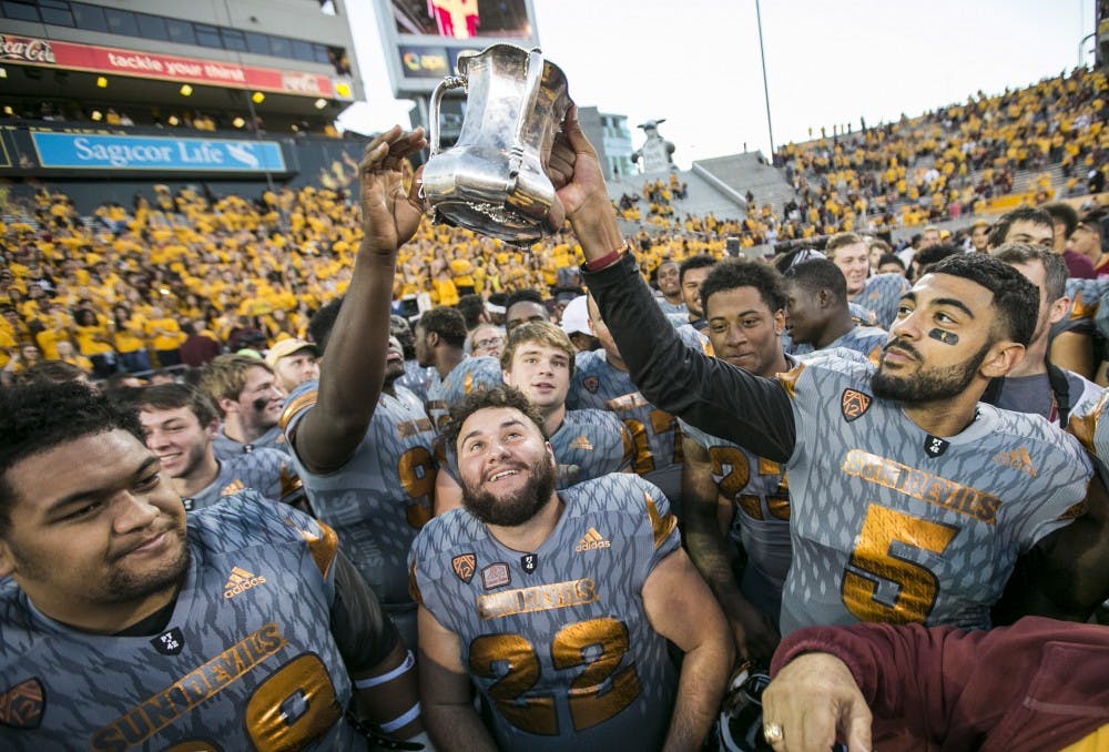 Sun Devil players hoist the Territorial Cup after winning a game against the Wildcats at Sun Devil Stadium in Tempe, Ariz., on Saturday, Nov. 21, 2015. The ASU Sun Devils took down the UA Wildcats, 52-36. 