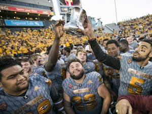 Sun Devil players hoist the Territorial Cup after winning a game against the Wildcats at Sun Devil Stadium in Tempe, Ariz., on Saturday, Nov. 21, 2015. The ASU Sun Devils took down the UA Wildcats, 52-36. 