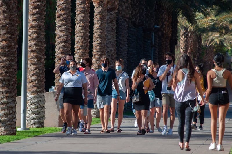 Estudiantes enmascarados caminan por Palm Walk en el campus de Tempe el jueves, 1 de abril de 2021. La Universidad anunció que el semestre de otoño de 2021 era probable que estuviera en el campus y en persona con sólo unos pocos cursos disponibles a través de ASU Sync.