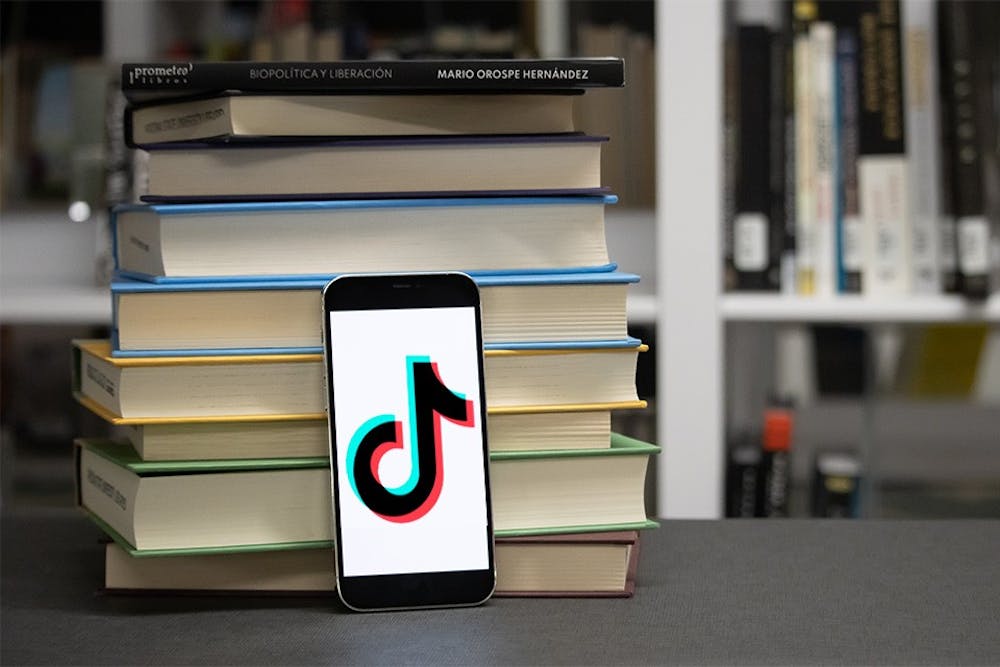 Photo illustration of a phone leaning up against a stack of books.