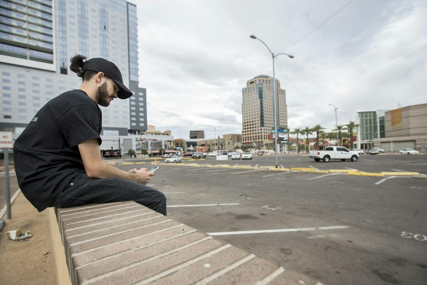 Gabriel Atwood, of Phoenix, waits to be picked up in a parking lot on the corner of First and Second streets and Washington and Jefferson streets on Monday, Sept. 26, 2016. The parking lot is the proposed site of a Fry's Foods grocery store and a high-rise residential complex. 