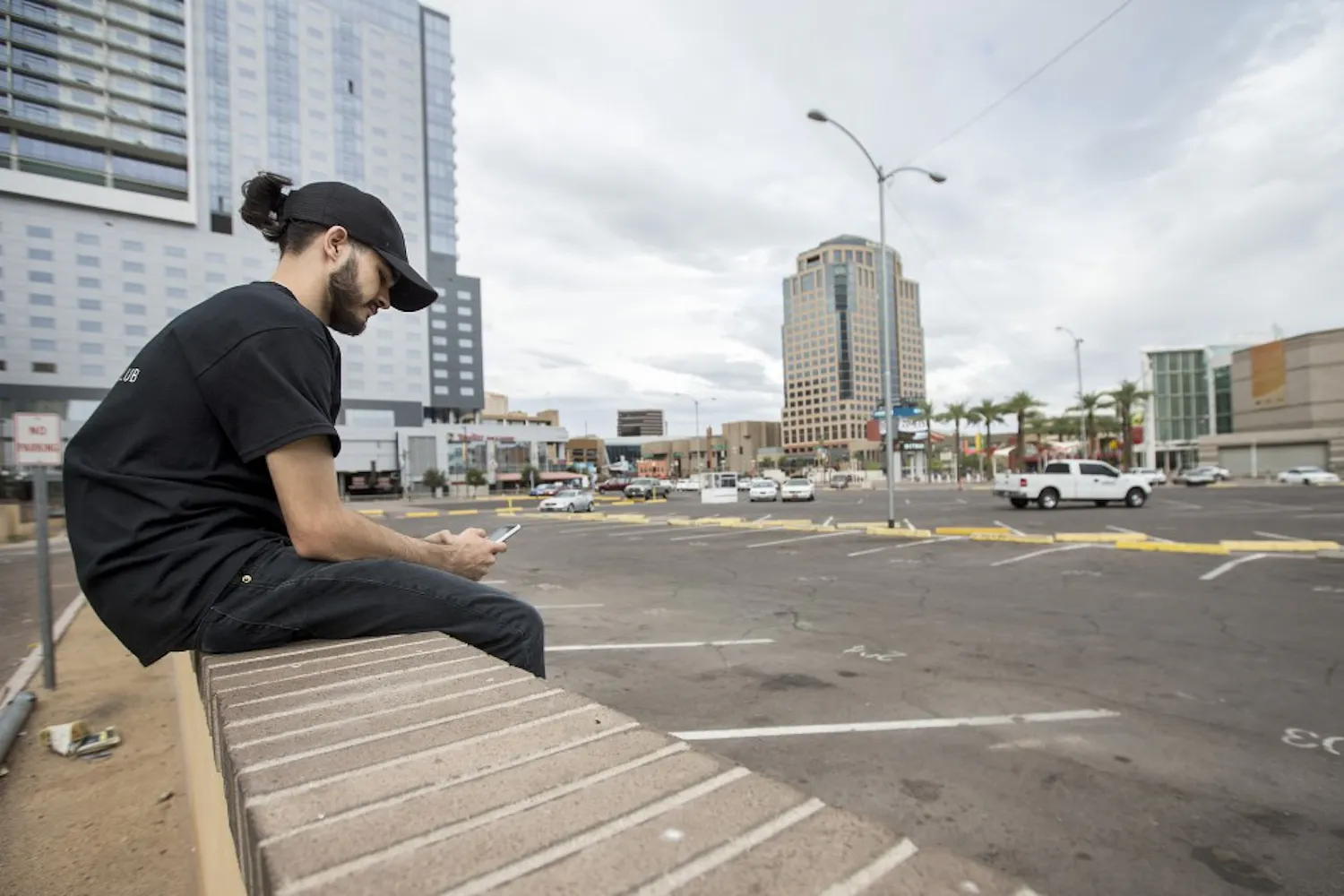Gabriel Atwood, of Phoenix, waits to be picked up in a parking lot on the corner of First and Second streets and Washington and Jefferson streets on Monday, Sept. 26, 2016. The parking lot is the proposed site of a Fry's Foods grocery store and a high-rise residential complex.