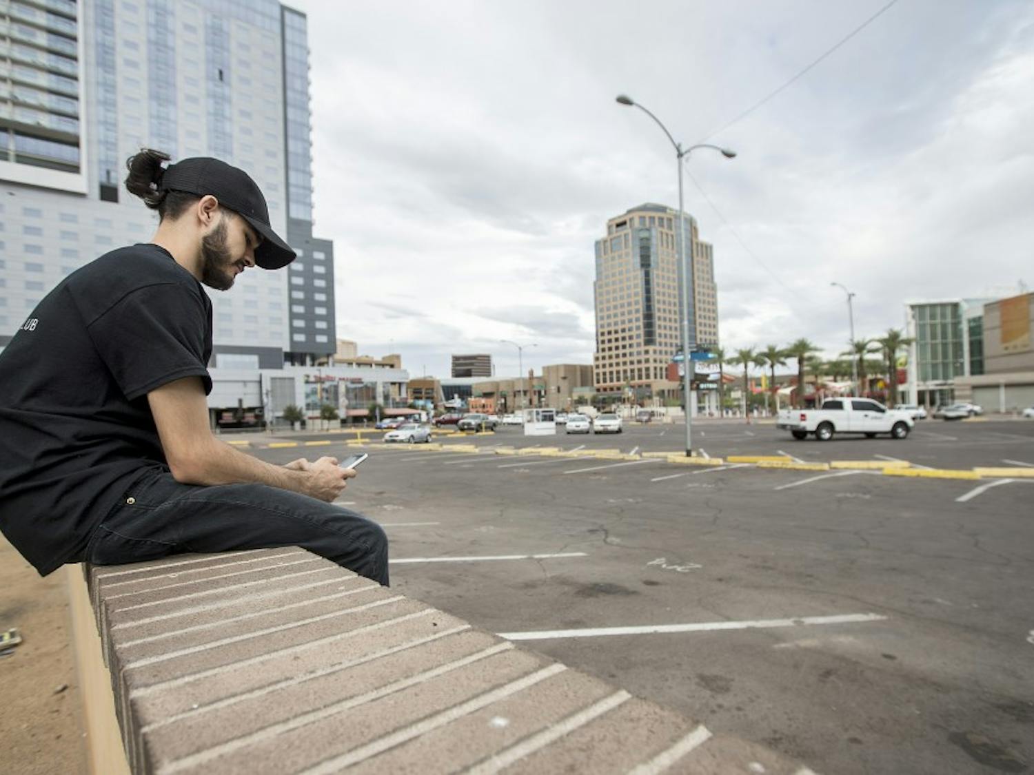 Gabriel Atwood, of Phoenix, waits to be picked up in a parking lot on the corner of First and Second streets and Washington and Jefferson streets on Monday, Sept. 26, 2016. The parking lot is the proposed site of a Fry's Foods grocery store and a high-rise residential complex. 