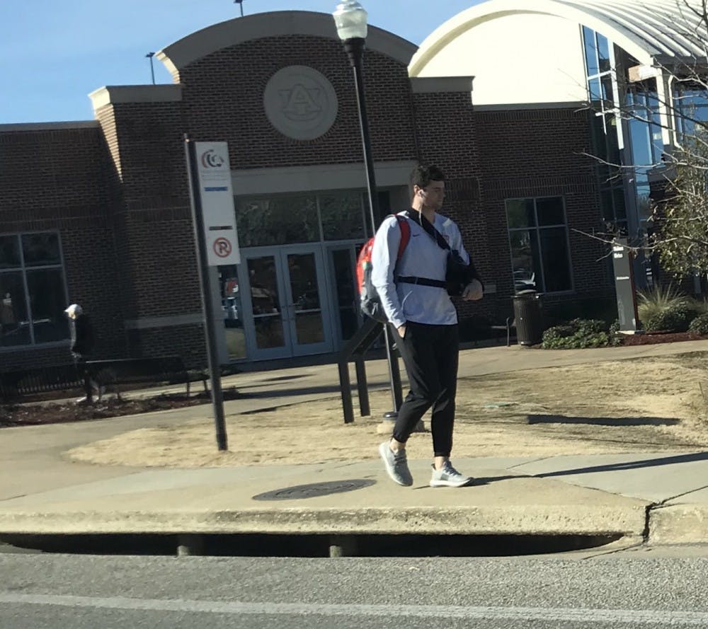 Auburn quarterback Jarrett Stidham walking on campus with a sling