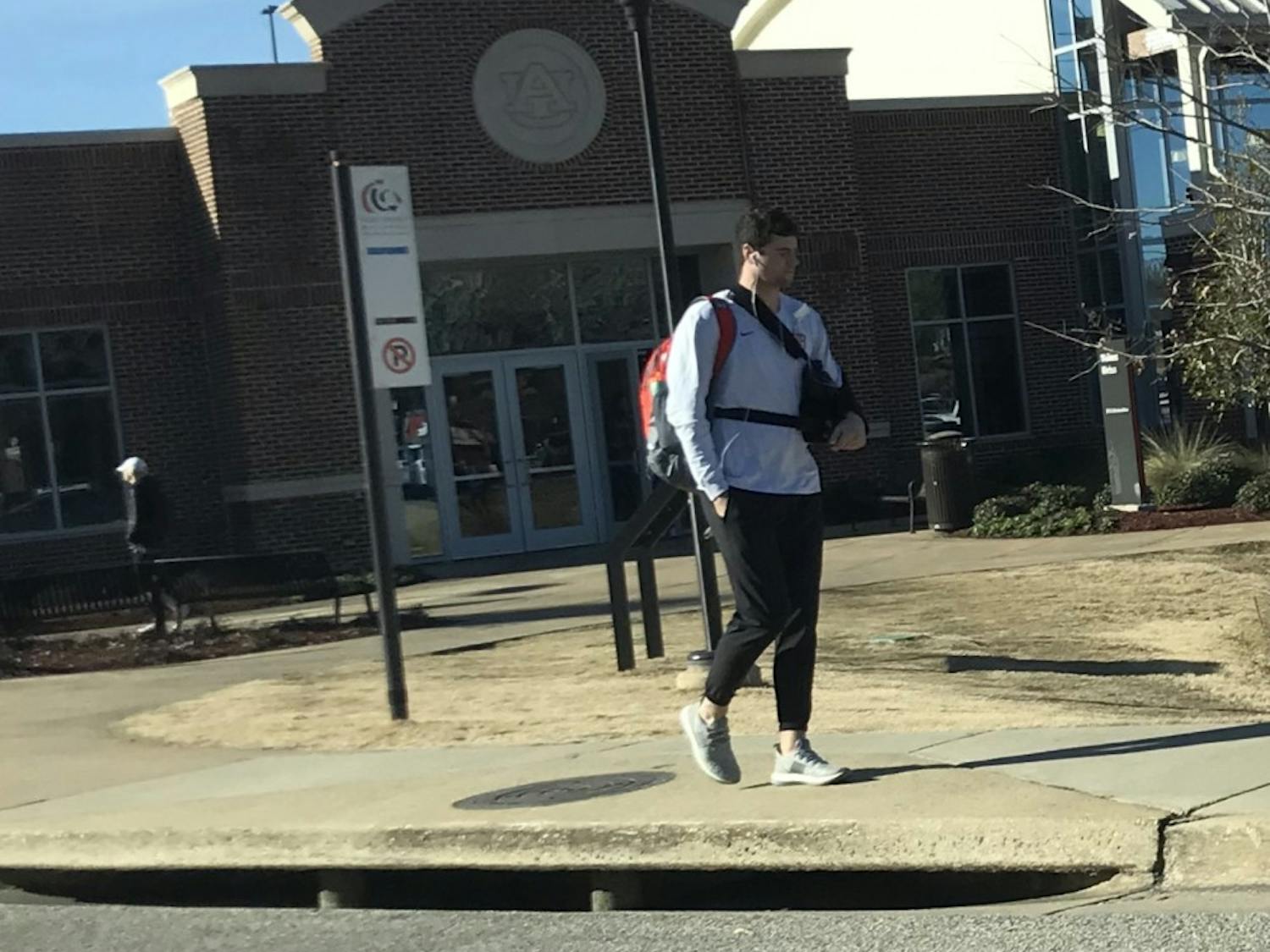 Auburn quarterback Jarrett Stidham walking on campus with a sling
