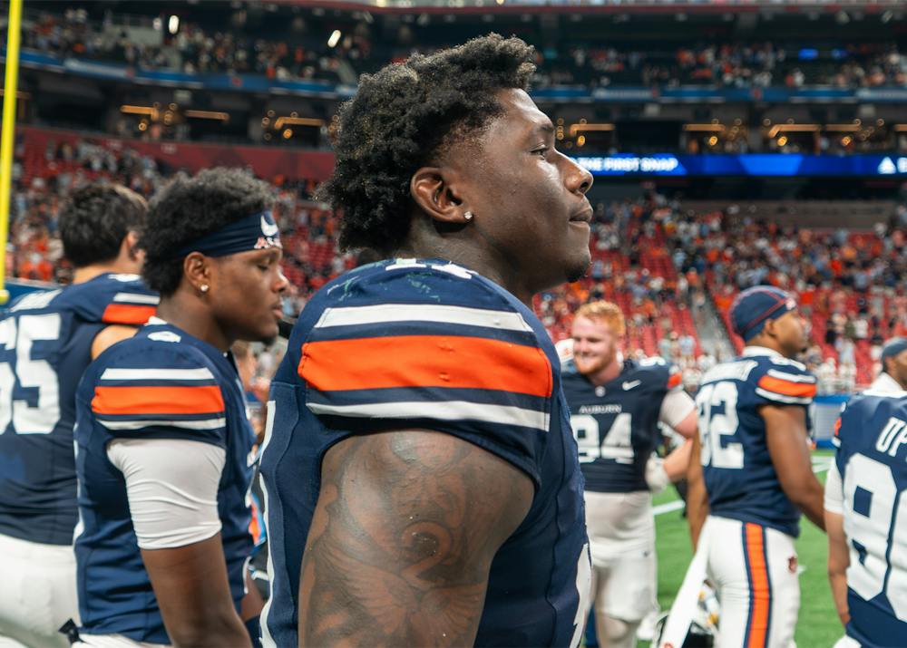 Auburn defensive lineman Xavier Atkins stands on the field following the Tigers’ win over Baylor, surrounded by teammates in Jordan-Hare Stadium.