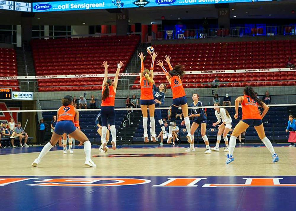 Auburn volleyball players jump at the net to block a South Alabama attack during a match at Neville Arena.
