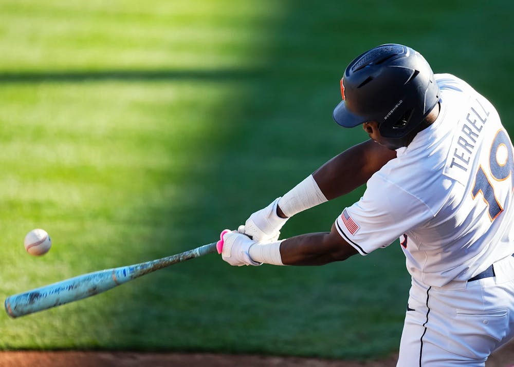 A baseball player in a white uniform with “TERRELL” and the number 19 on the back swings a bat, making contact with a pitch as the ball flies off to the left. He wears a dark helmet and batting gloves, and the action is captured mid-swing against a blurred green outfield background.
