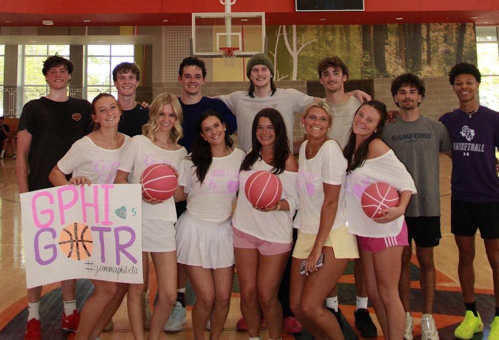 Male and female Auburn student participants of the Gamma Phi Beta Moonball tournament taking a group photo on the court.