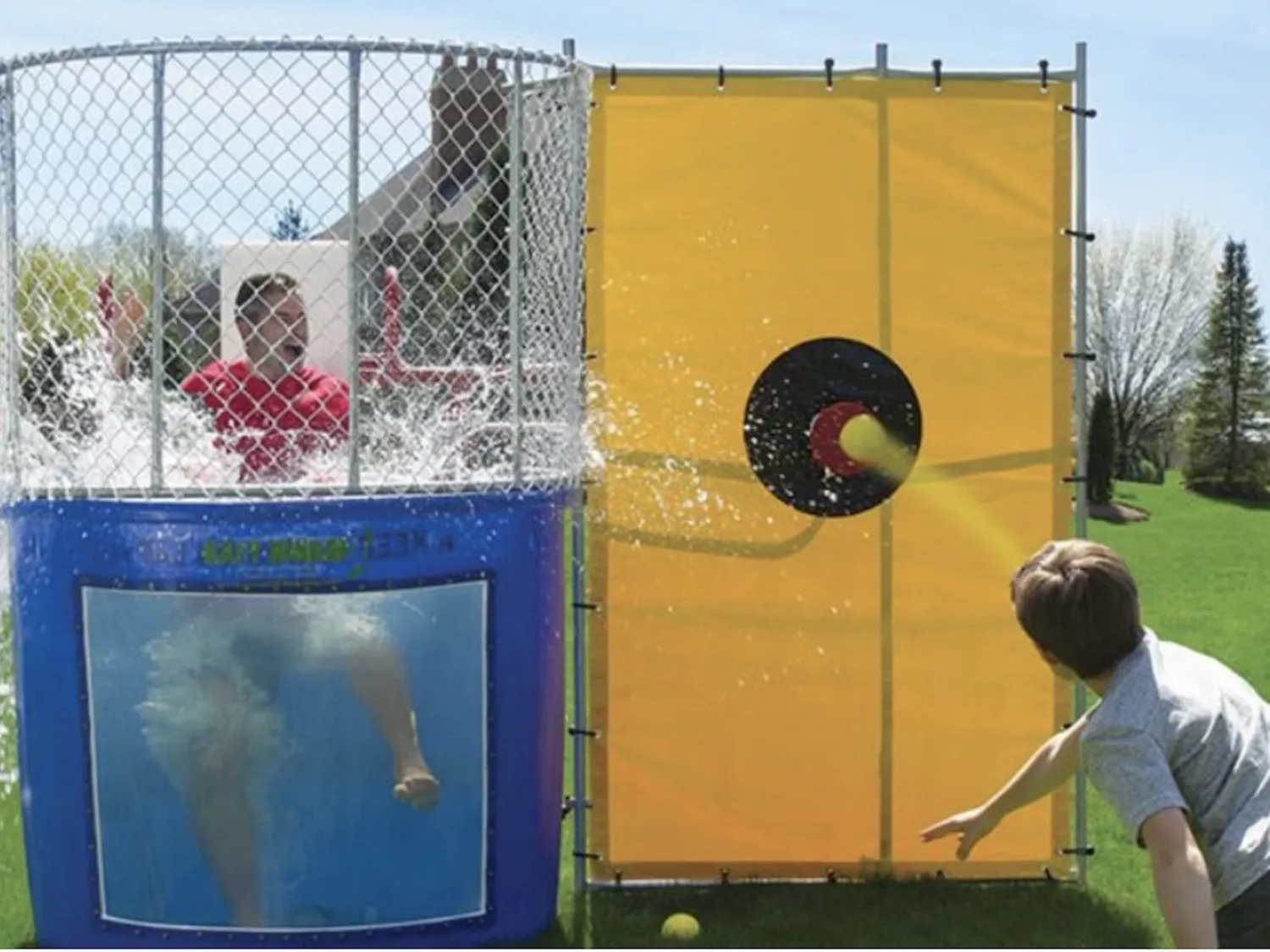 A participant throws a ball at a dunk tank target as water splashes around a person in a red shirt during the 2025 Beat Bama Food Drive.