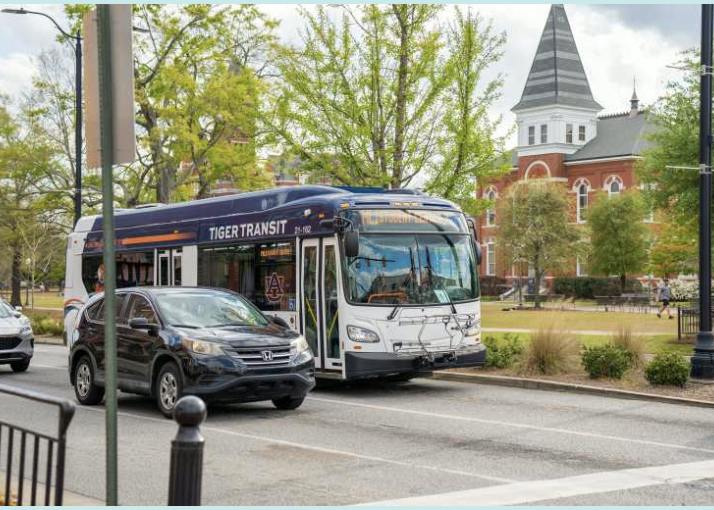 A Tiger Transit bus travels along College Street in Auburn, Alabama, with Samford Hall visible behind it