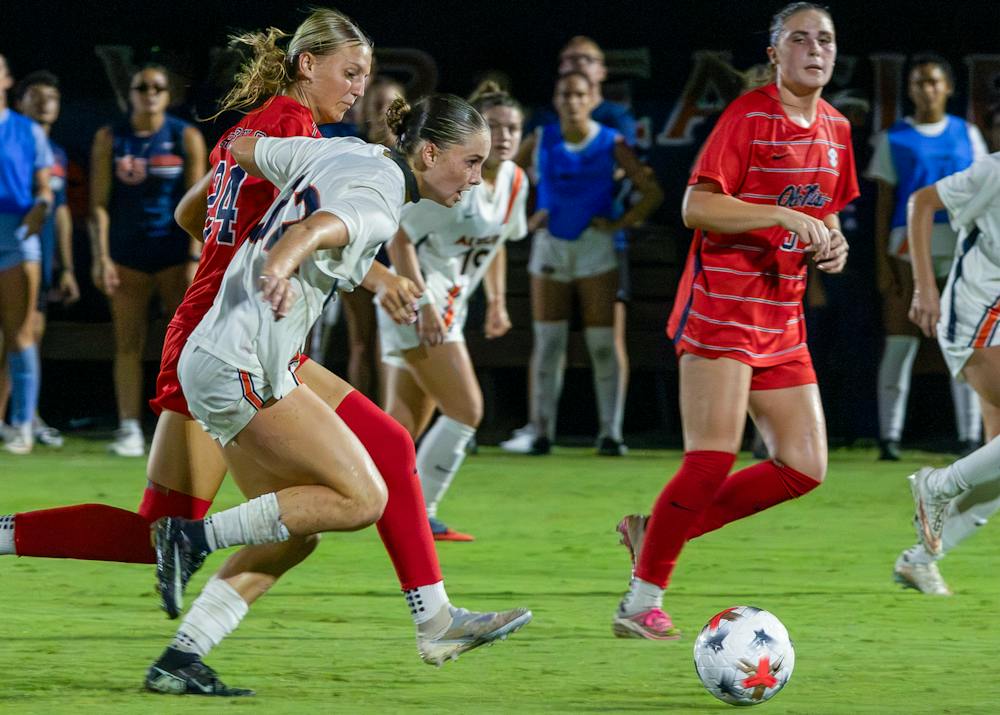 Auburn soccer’s No. 32 Kelly Gordon battles for the ball against Ole Miss at Auburn. Gordon runs alongside an Ole Miss player as the ball rolls ahead on the field.