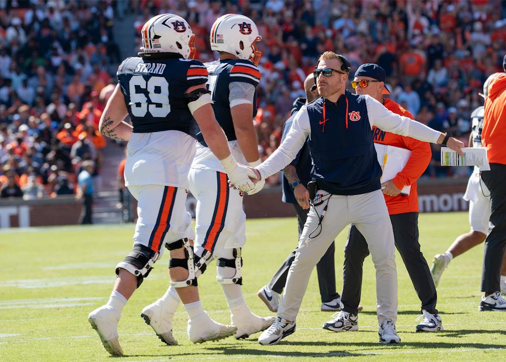 Auburn head coach Alex Golesh high-fives players as they leave the field during the game against LSU at Jordan-Hare Stadium.