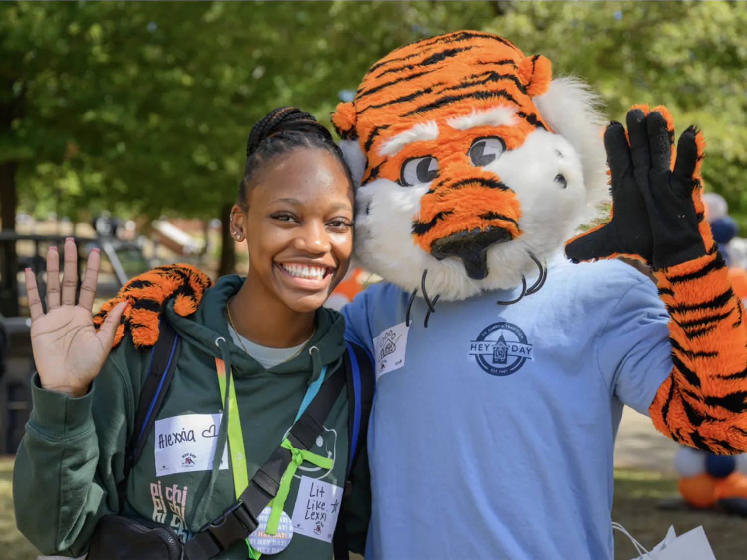 Aubie hugs a smiling woman at Auburn’s Hey Day as they pose for a photo and wave.