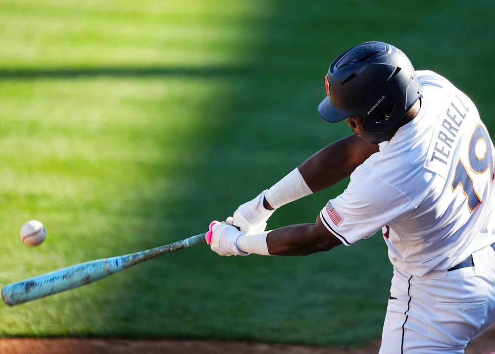 A baseball player in a white uniform with “TERRELL” and the number 19 on the back swings a bat, making contact with a pitch as the ball flies off to the left. He wears a dark helmet and batting gloves, and the action is captured mid-swing against a blurred green outfield background.