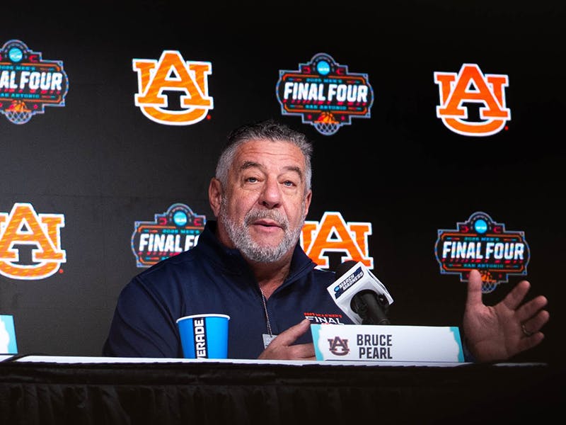 Auburn men’s basketball coach Bruce Pearl speaks at a press conference during the NCAA Final Four, with Auburn logos and Final Four signage displayed on the backdrop.