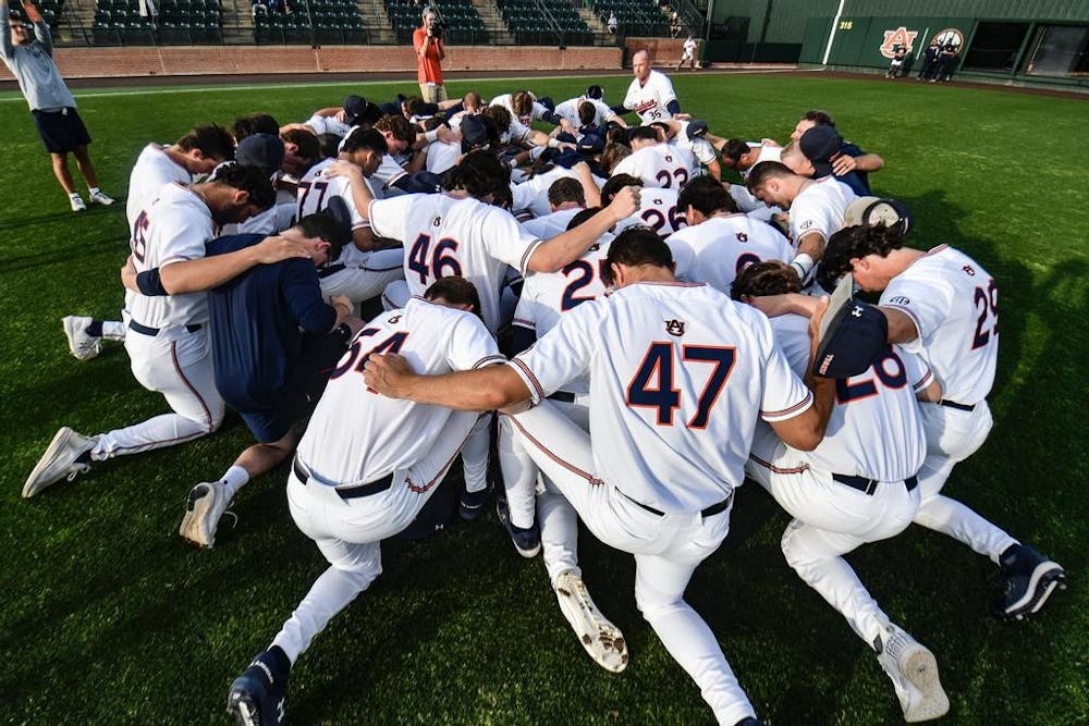 <p>Auburn baseball players kneel in prayer before their game against North Alabama on March 28th, 2023.</p>