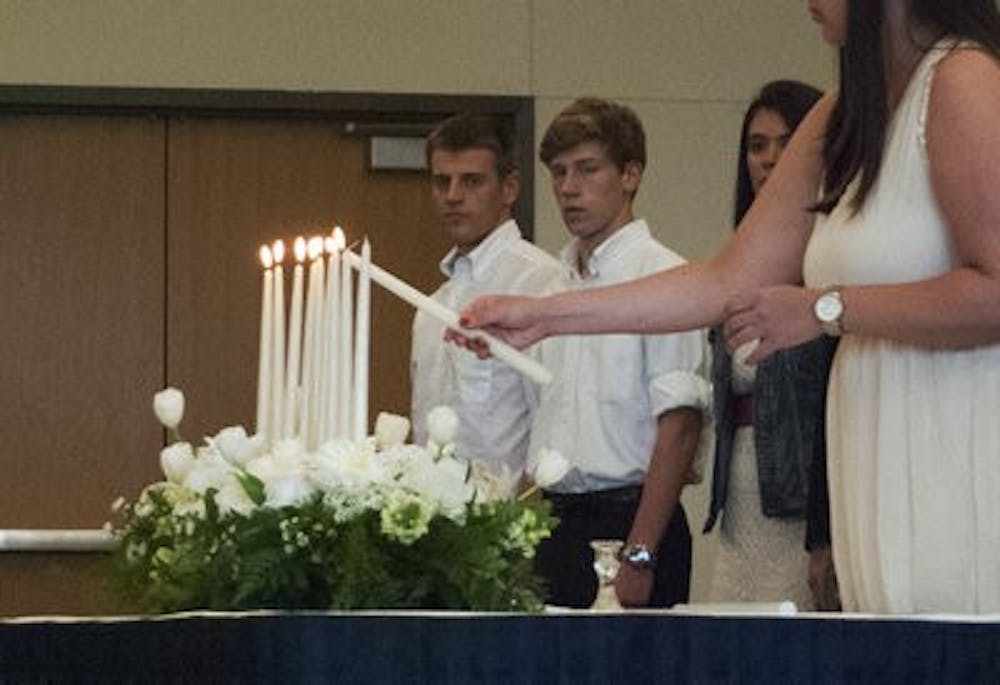 Family and friends light candles in memory of the students who have passed. (Emily Enfinger| ASSISTANT PHOTO EDITOR)