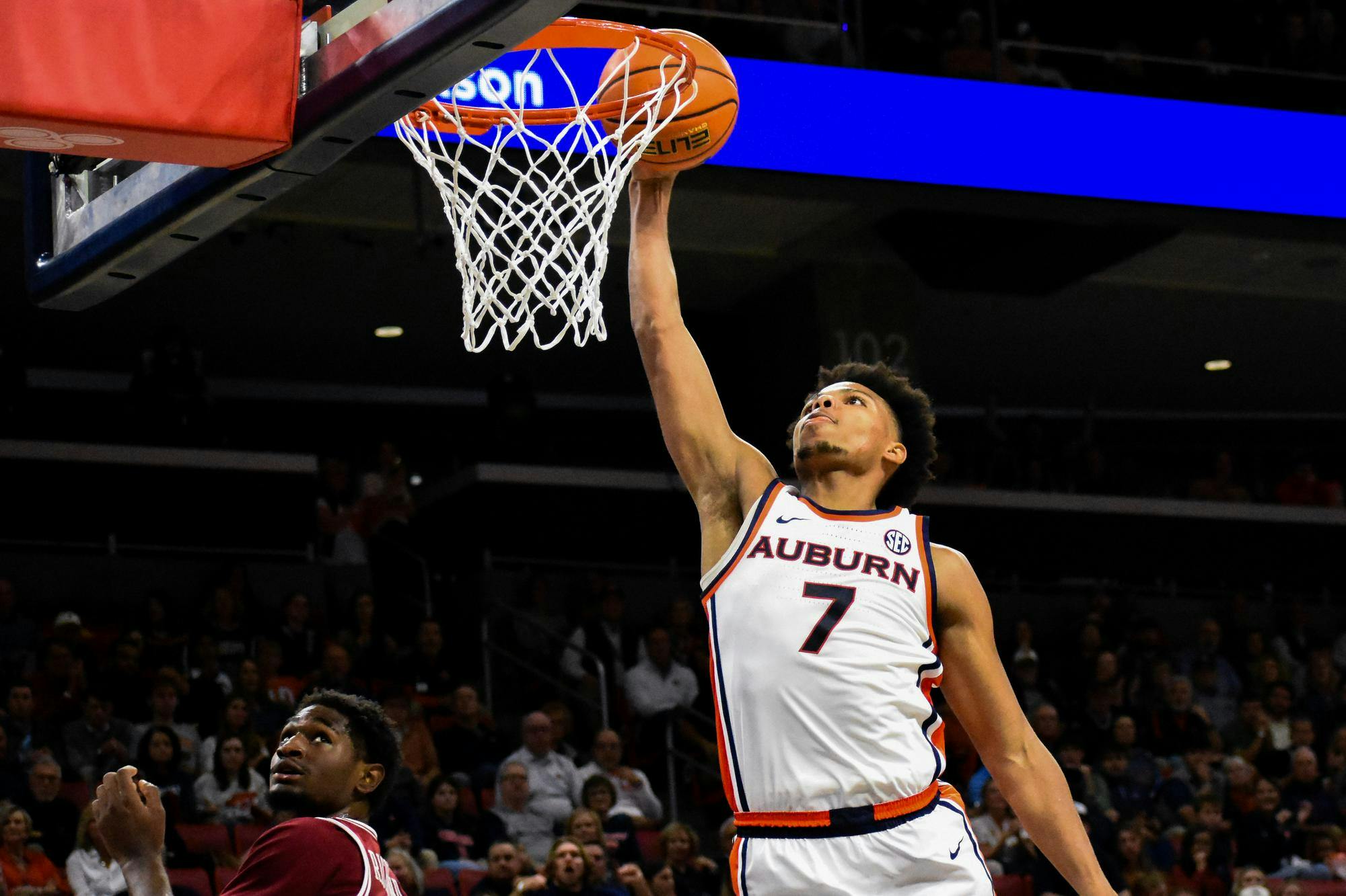 A basketball player in an Auburn jersey leaps to score while another player looks on from below.