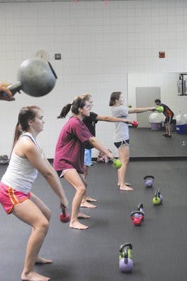 Students swing kettle bells in one of the Student ACT's exercise classes Thursday. (Christen Harned / ASSISTANT PHOTO EDITOR)