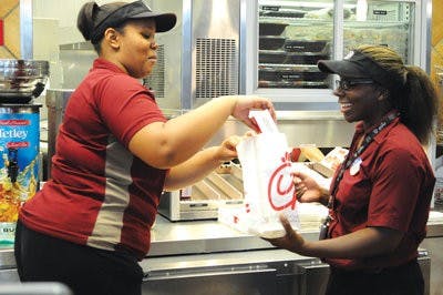 Tiera Frazier prepares a chicken-nugget meal for a customer with Kiejuan Simmons at the Chick-fil-A in the Student Center. (CHRISTEN HARNED / ASSOCIATE PHOTO EDITOR)