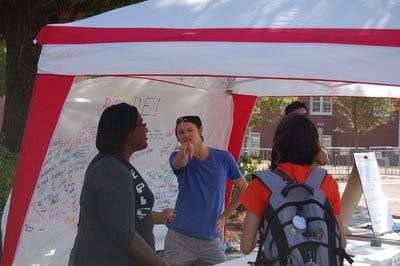 Braxton Tanner, sophomore in zoology and director of political affairs with AGSA, dances on the concourse Monday as passing students sign messages of love on National Coming Out Day. (Brian Woodham / Associate Copy Editor)