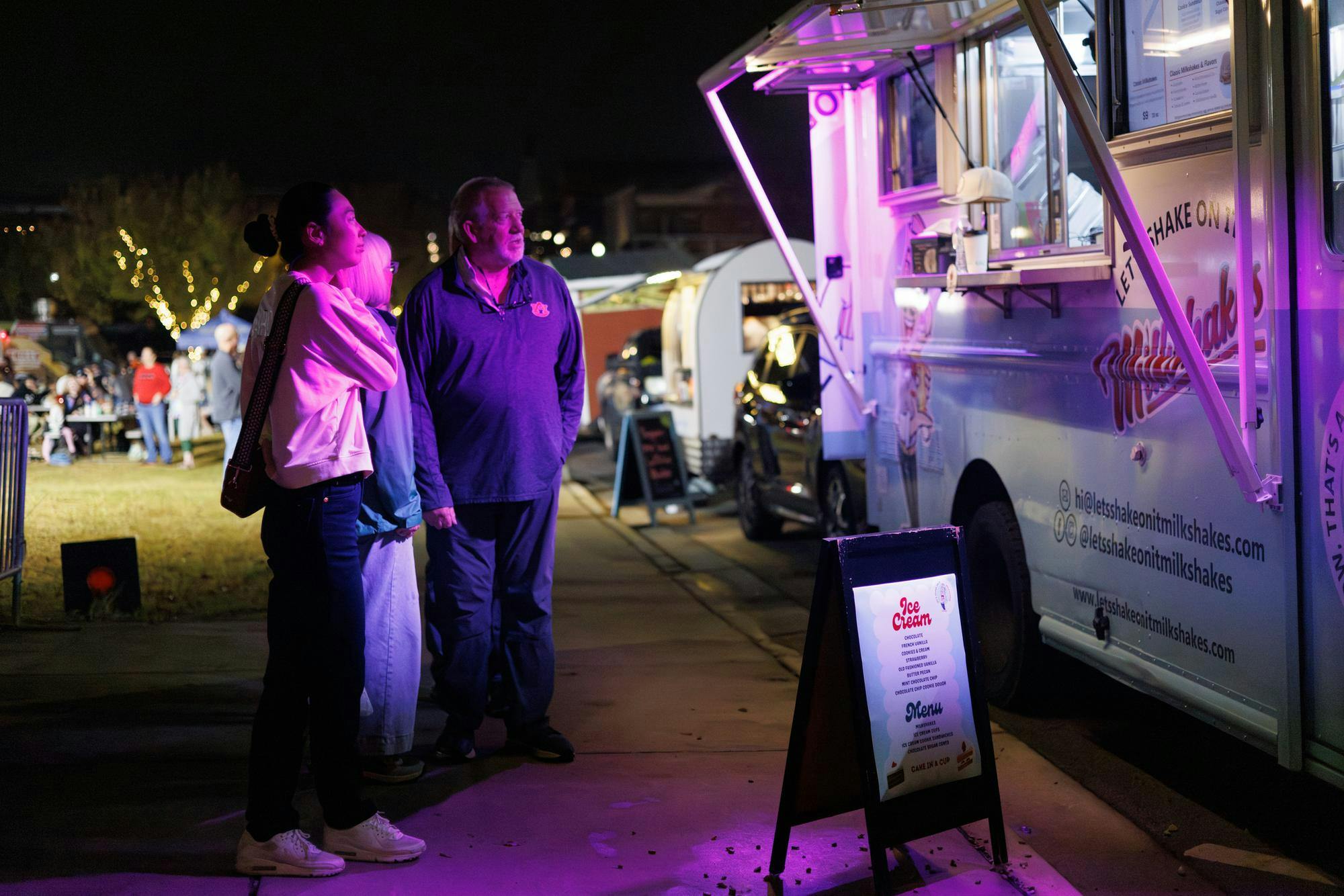 A family stands in front of a food truck named "Let's Shake on it Milkshake" during Food Truck Friday in downtown Opelika, Alabama on Nov. 21, 2025.