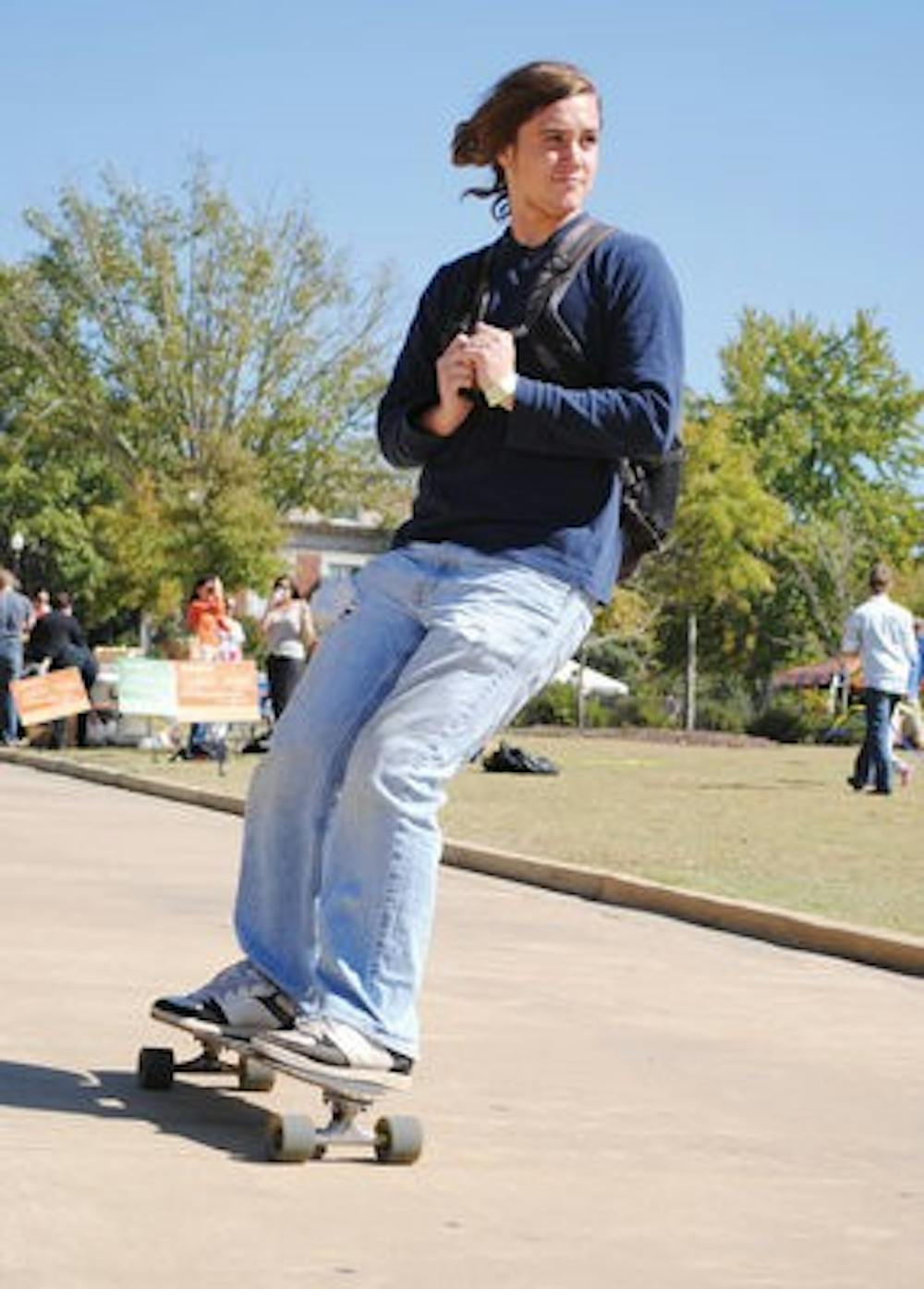 Sean Frost, senior in psychology, rides a longboard down the Thach concourse Friday on his way to class. (Maria Iampietro / Associate Photo Editor)