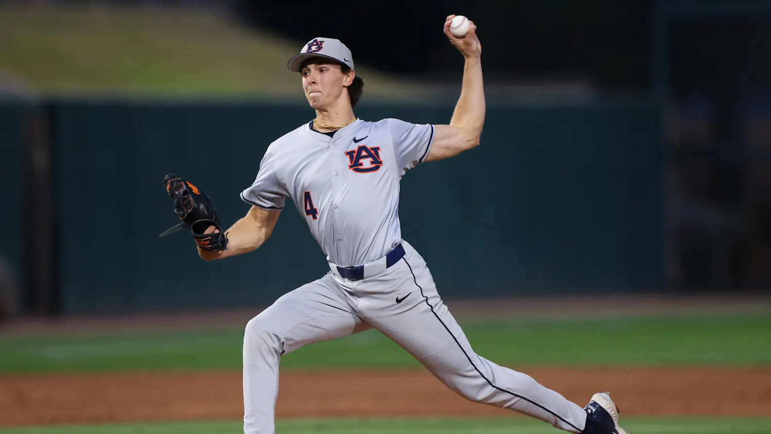 A baseball player in a gray uniform is winding up to throw a ball on a field.