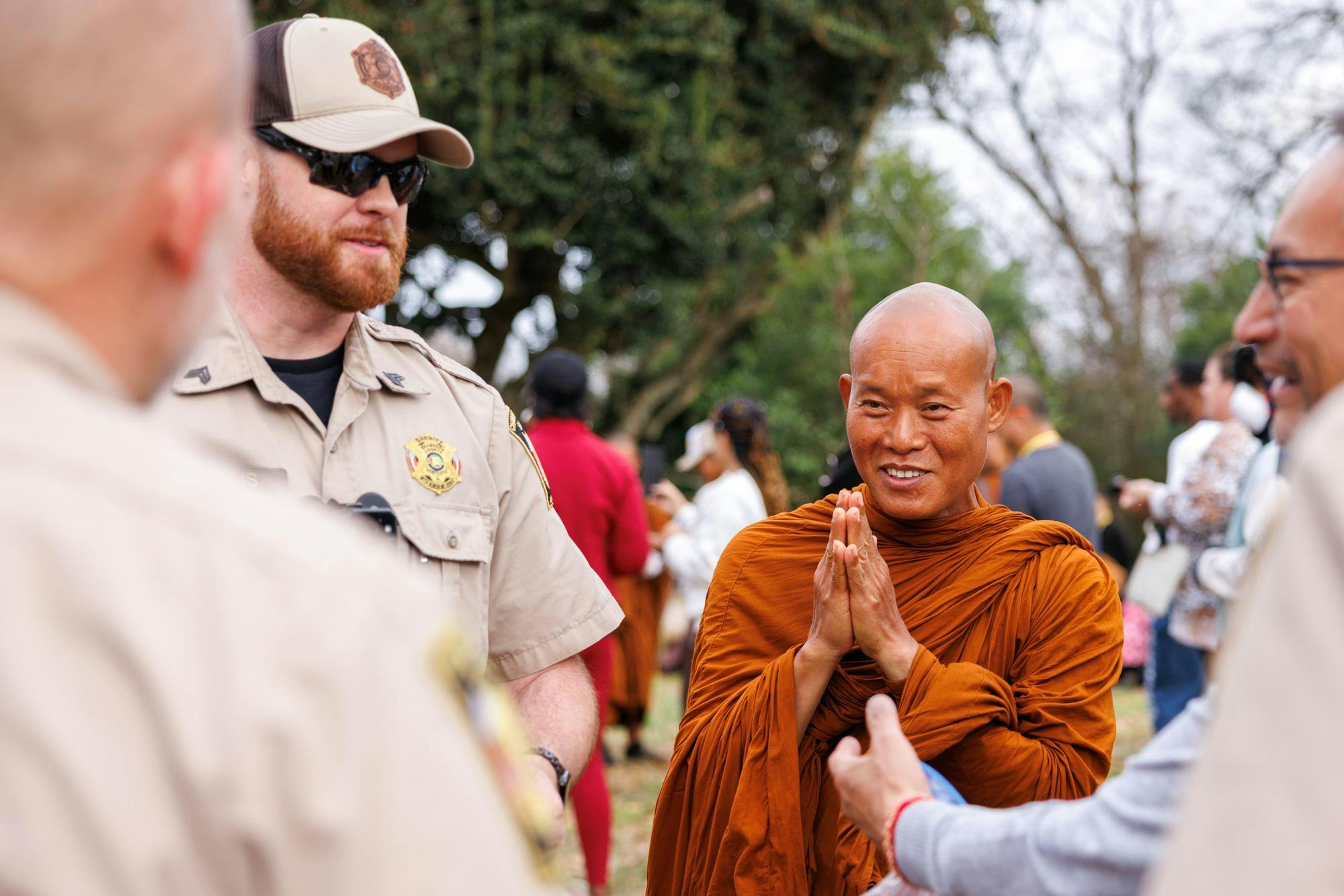 A venerable monk presses his palms together and points fingers upwards towards a group of Chambers County Deputy Sheriffs in a gesture of deep respect. The Walk for Peace has a police escort for safety, traffic management and crowd control.