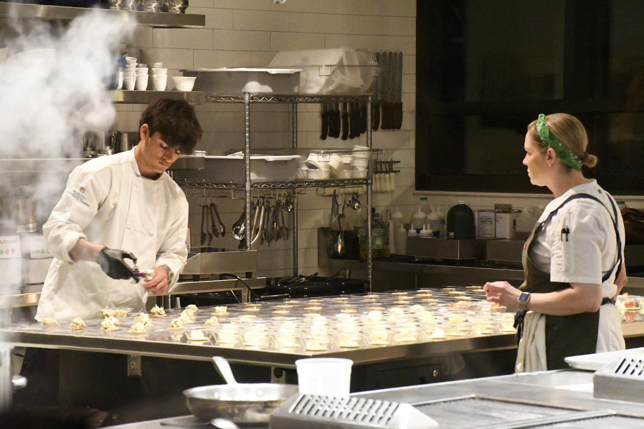 Two assistant chefs preparing more servings in the kitchen during the Children’s Table event on Tuesday, March 3, 2026.