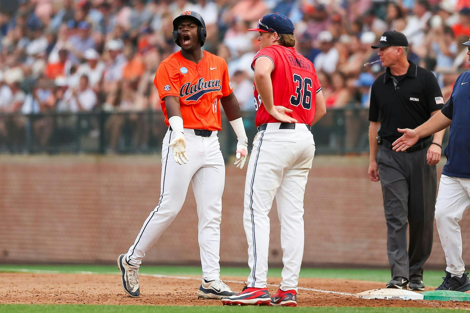 A player in an orange uniform celebrates loudly while another in a red uniform stands nearby, and umpires observe the scene.