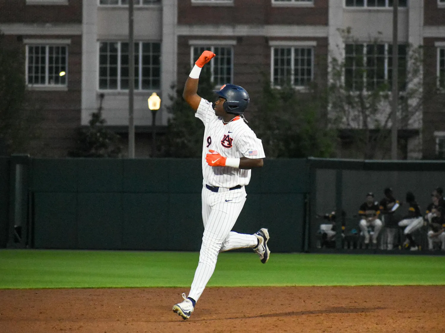 A baseball player in a white jersey with blue and orange accents celebrates on the field during a game.