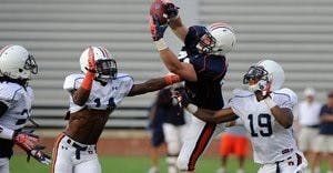 Auburn's Philip Lutzenkirchen catches a pass behind defenders, from left, T'Sharvan Bell, Erique Florence and Ryan White. (Courtesy of Todd Van Emst)