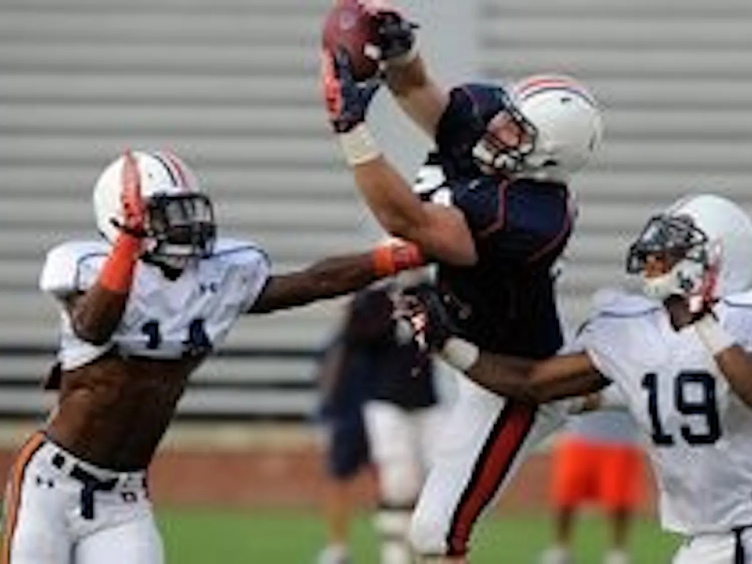 Auburn's Philip Lutzenkirchen catches a pass behind defenders, from left, T'Sharvan Bell, Erique Florence and Ryan White. (Courtesy of Todd Van Emst)