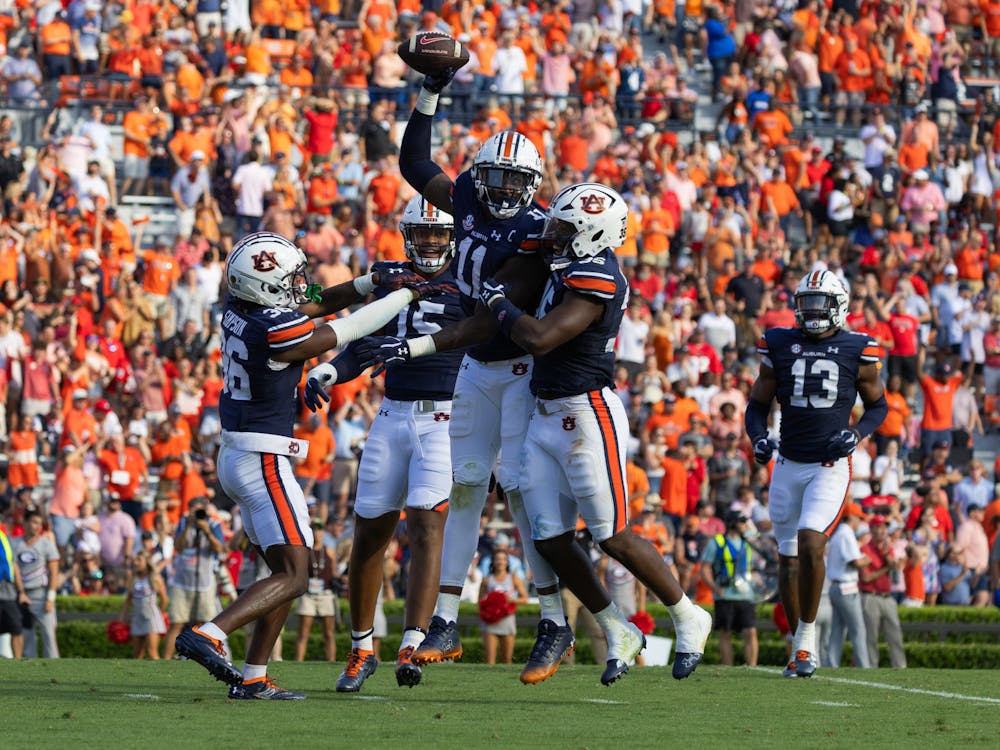 Elijah McAllister holds up the football in triumph after the Auburn defense forces a turnover versus Georgia