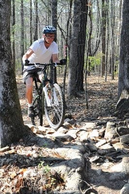 Brad Hooks rides his mountain bike up a rocky slope on the bike trail at Lake Wilmore near Ogletree Elementary School. (Christen Harned / Assistant Photo Editor)