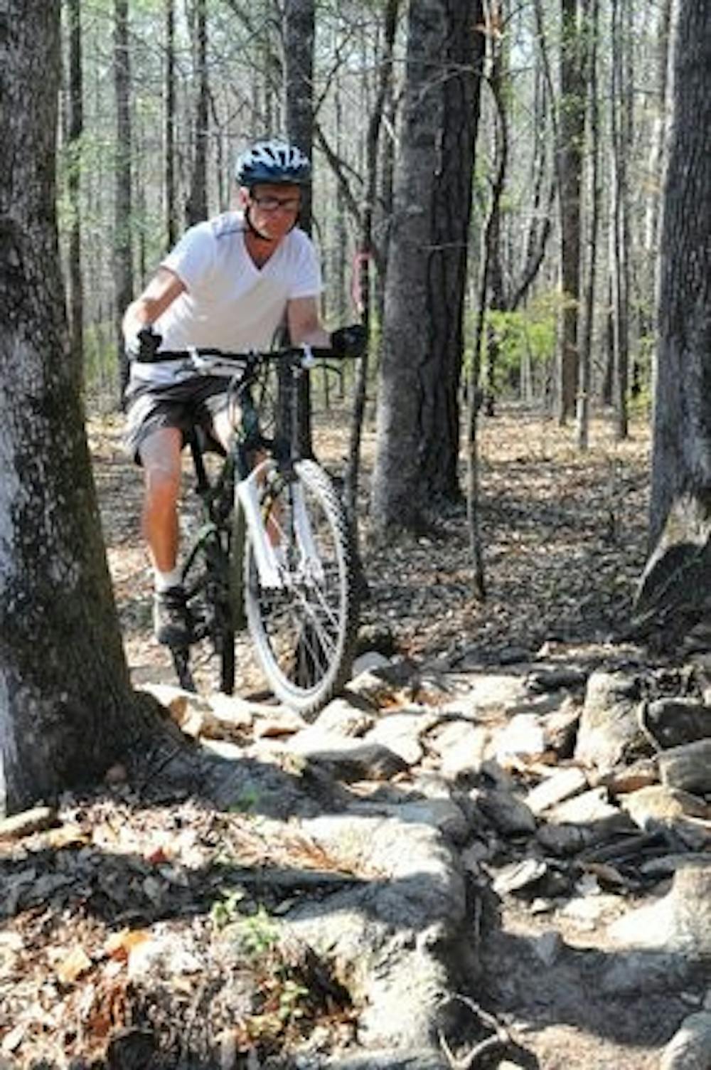 Brad Hooks rides his mountain bike up a rocky slope on the bike trail at Lake Wilmore near Ogletree Elementary School. (Christen Harned / Assistant Photo Editor)