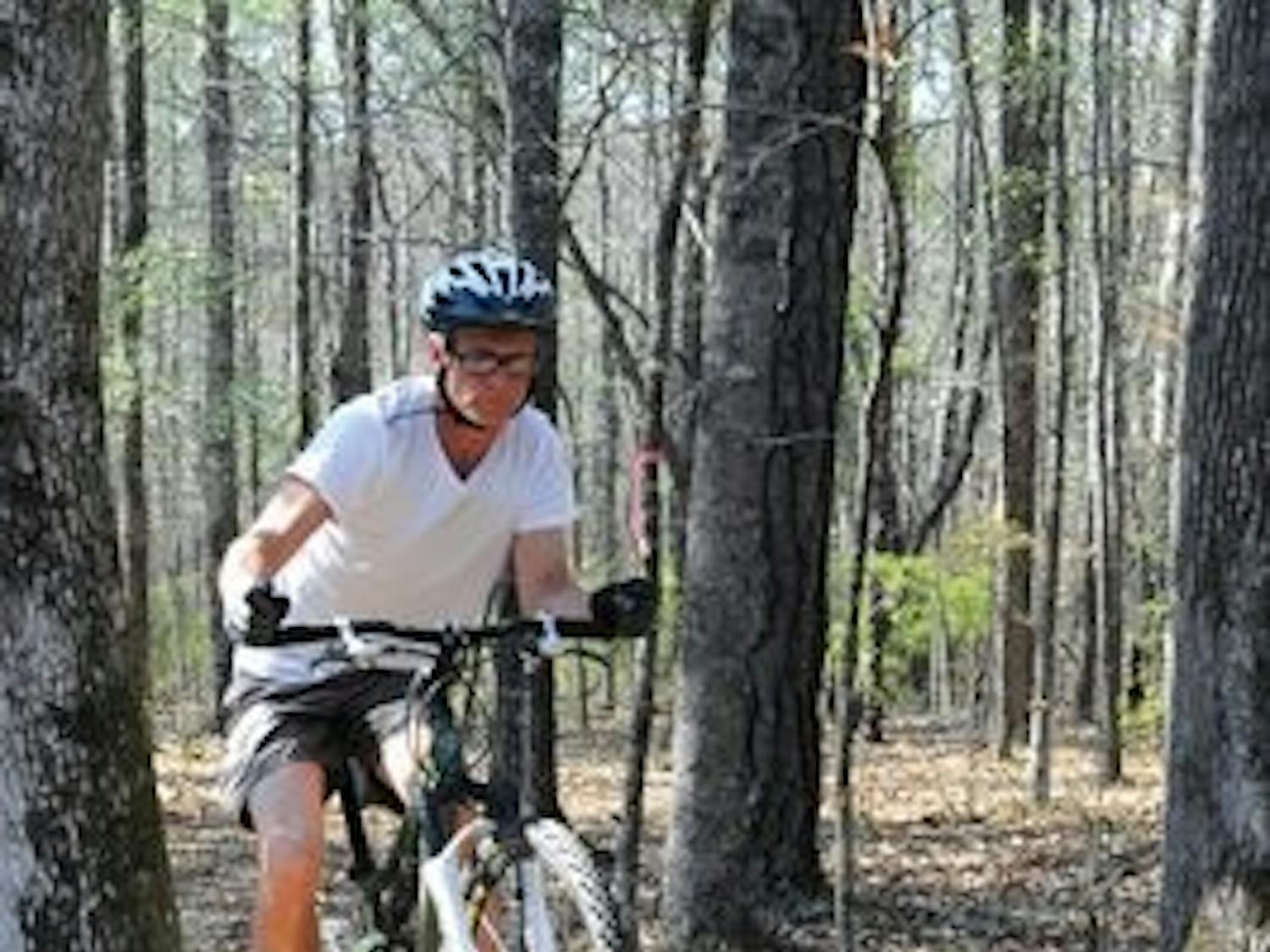Brad Hooks rides his mountain bike up a rocky slope on the bike trail at Lake Wilmore near Ogletree Elementary School. (Christen Harned / Assistant Photo Editor)
