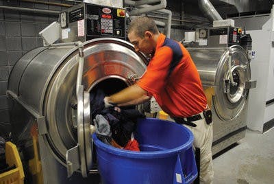 An athletic equipment staffer takes football uniforms out of the washing machine in the Athletic Complex. (Maria Iampietro/ Associate Photo Editor)