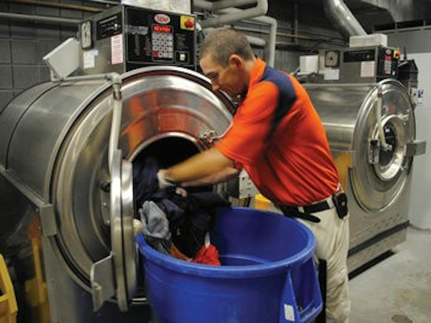 An athletic equipment staffer takes football uniforms out of the washing machine in the Athletic Complex. (Maria Iampietro/ Associate Photo Editor)