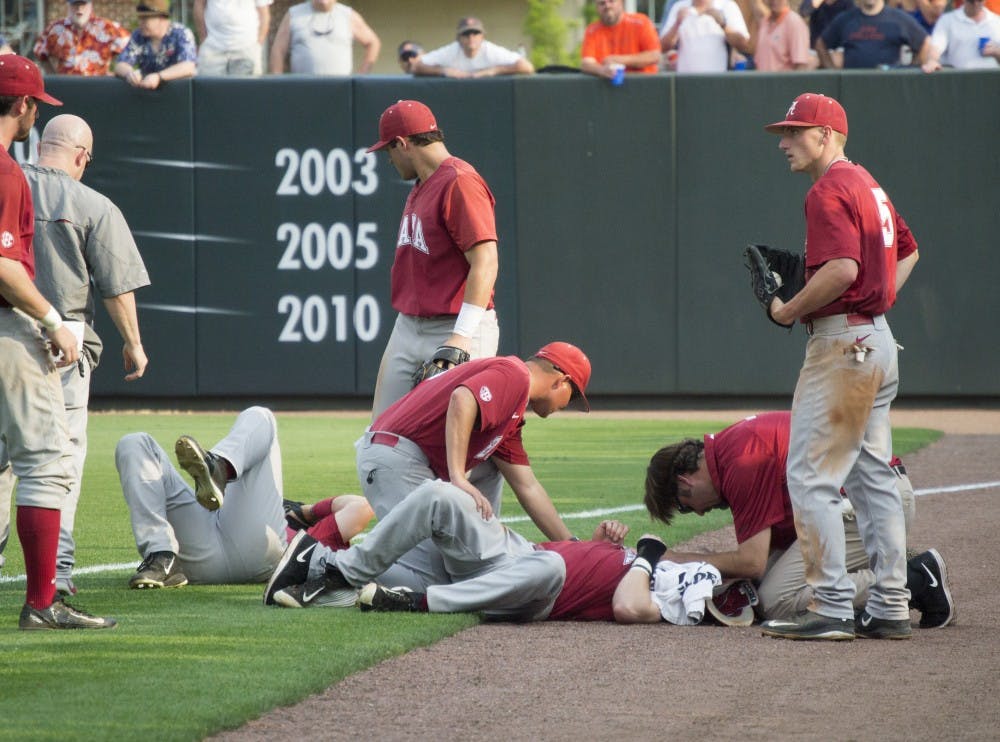 Alabama players Chance Vincent (middle, ground) and Casey Hughston (left, ground) receive medical attention after colliding in the outfield. (Jordan Hays | Copy Editor)