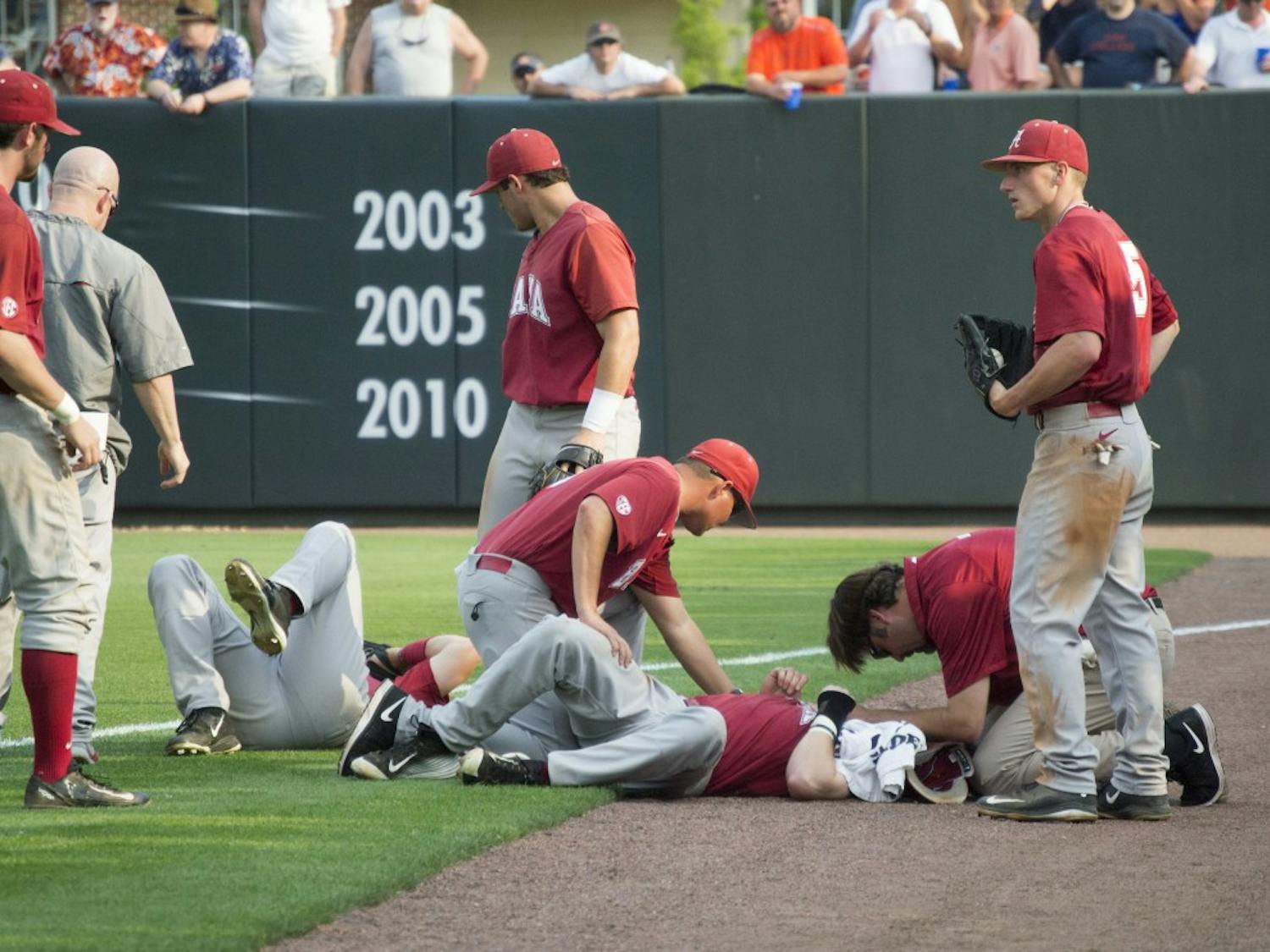 Alabama players Chance Vincent (middle, ground) and Casey Hughston (left, ground) receive medical attention after colliding in the outfield. (Jordan Hays | Copy Editor)